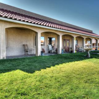 A beautiful house with a spacious garden and porch under clear blue skies.