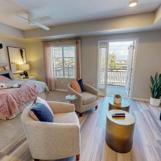 A stylish modern bedroom with cozy seating, elegant decor, and access to a balcony.