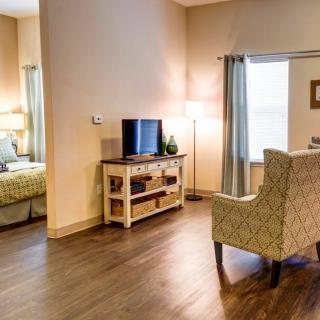 A cozy living space featuring a TV, lamp, and comfortable chair with an adjacent bedroom.