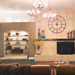 A cozy and elegantly decorated living room featuring a stylish clock, well-arranged shelves, and a warm ambiance.