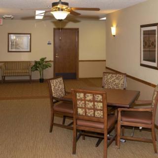 A cozy lobby area featuring a table with chairs, wall art, and soft lighting.