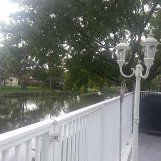 A scenic view of a riverside with a white fence and lamp post.