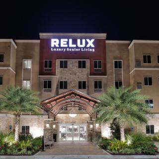The illuminated entrance of Relux Luxury Resort at night, surrounded by palm trees.