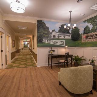 A warmly lit hallway with a mural, featuring comfortable seating and elegant decor.