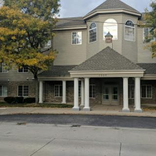 A modern building featuring a welcoming entrance with columns and surrounded by trees.