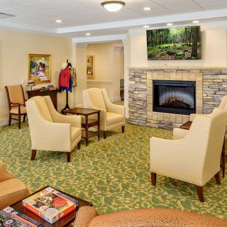 A cozy living room with comfortable seating around a fireplace and a television mounted above.