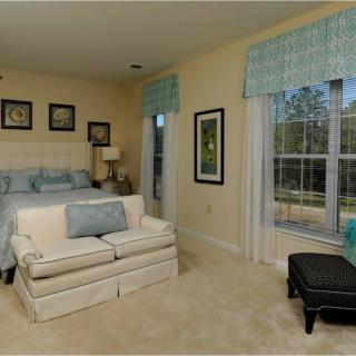A cozy bedroom featuring a bed, small sofa, and large window with calming decor.