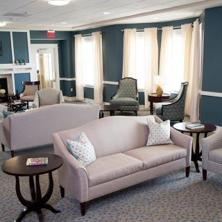 A cozy living room with sofas and armchairs arranged around small tables, featuring warm lighting and elegant decor.