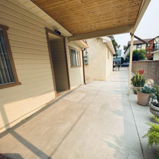 A covered patio with a concrete floor and potted plants, providing an inviting outdoor space at a residential property.