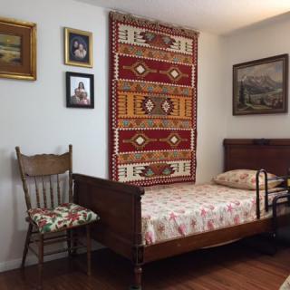 A cozy bedroom featuring a wooden bed, decorative tapestry, and vintage wall art.