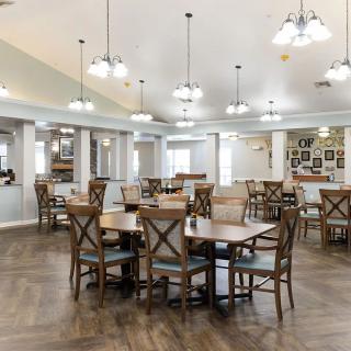 A spacious and well-lit dining area with wooden tables and chairs, featuring elegant lighting fixtures.