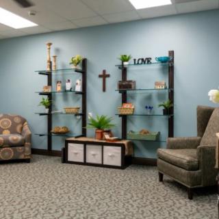 A cozy living room with blue walls, featuring comfortable chairs and decorated shelves.