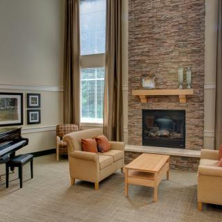 A cozy living room with modern furniture, featuring a piano and a fireplace.