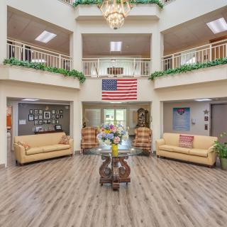 A spacious lobby with a chandelier, seating area, and an American flag on display.