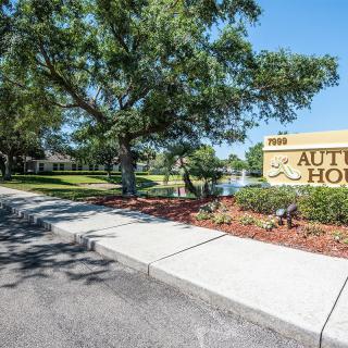 A landscaped entrance with a welcoming sign and walkway surrounded by trees.