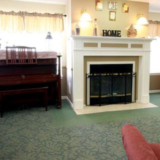 A cozy living room featuring a fireplace and a piano, with soft lighting and homey decor.