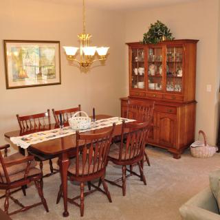 A cozy dining room with a wooden table and chairs, accompanied by a matching china cabinet and an elegant chandelier.