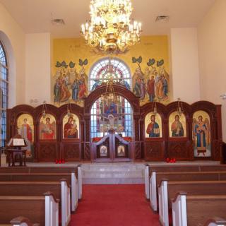 Interior of an Orthodox church featuring an iconostasis and a grand chandelier.
