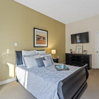 A cozy bedroom featuring a neatly made bed, a wall-mounted TV, and tasteful decor.