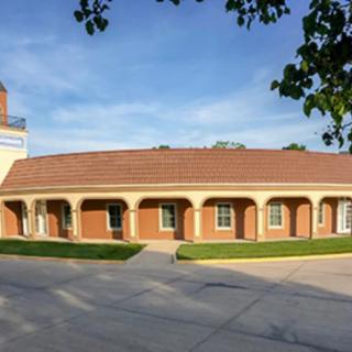 A brick building with a tiled roof and columns in the front, set under a clear blue sky.