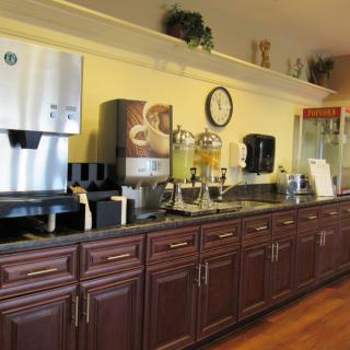 A well-equipped hotel breakfast area featuring a coffee machine, juice dispensers, and other beverage options.