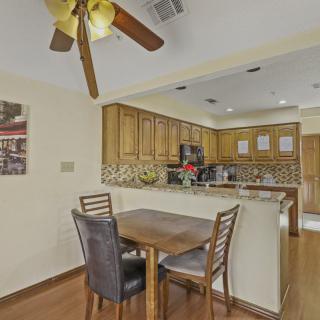 A cozy dining area connected to a kitchen with wooden cabinetry and a ceiling fan.