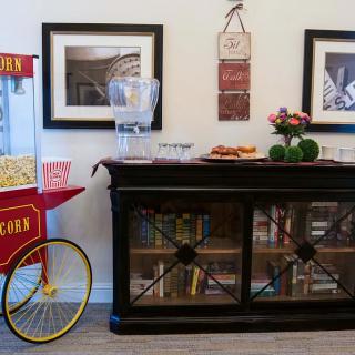 A cozy snack corner featuring a vintage popcorn machine, a well-stocked bookshelf, and decorative framed pictures.