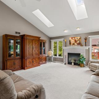 A cozy living room with skylights, featuring a fireplace and comfortable seating.