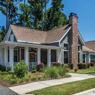 A charming residential house with a porch, landscaped front yard, and prominent chimney.
