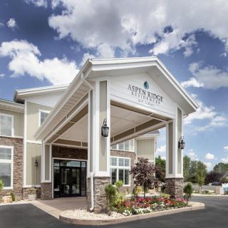 Entrance of a modern hotel with classic architectural design under a partly cloudy sky.
