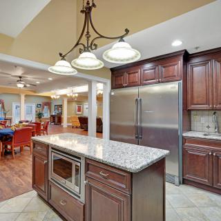 A modern kitchen with an island, featuring wood cabinets and a granite countertop, within an open floor plan.