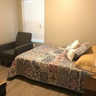 A cozy bedroom with a quilt-covered bed and an armchair near the window.