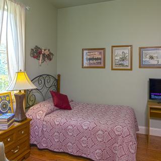 A cozy bedroom with a patterned bedspread, wall art, and natural light.