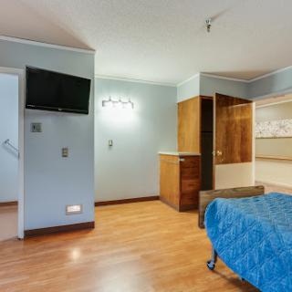 A modern bedroom with a wooden floor, featuring a television and minimalist furniture.