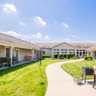 A sunny courtyard with a meandering pathway and well-maintained lawn, surrounded by residential buildings.