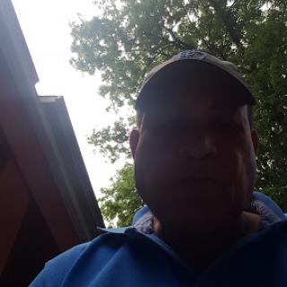 A person wearing a hat and a blue shirt appears to be outdoors.