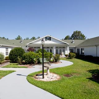 A well-maintained building with a surrounding lawn and pathway on a clear day.