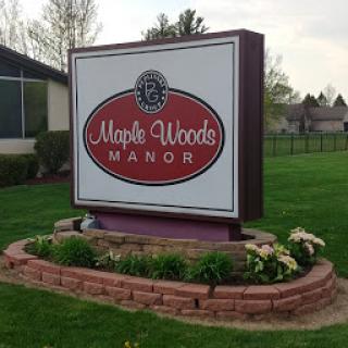 The welcoming entrance sign of Maple Woods Manor, surrounded by a well-maintained garden.