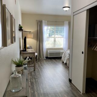 A modern and minimalist bedroom interior with sleek flooring, stylish decor, and natural lighting from a large window.