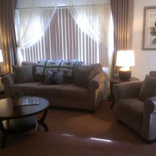 A cozy living room with a sofa, armchair, coffee table, and soft lighting.