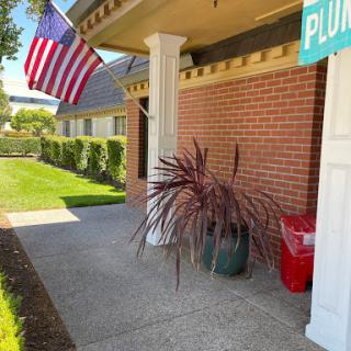 An inviting entrance featuring an American flag, colorful plants, and a well-maintained sidewalk.