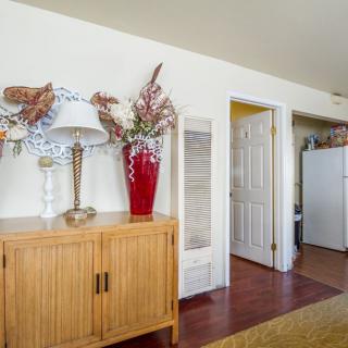 A cozy living space featuring a wooden cabinet with decorative items and a view into the kitchen.