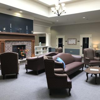 A cozy living room with a fireplace, sofas, and chairs arranged for conversation.
