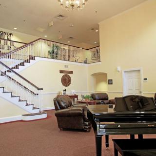A spacious lobby with a grand staircase, comfortable seating, and a grand piano.