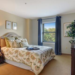 A cozy bedroom with elegant bedding, a scenic view through the window, and tasteful decor.