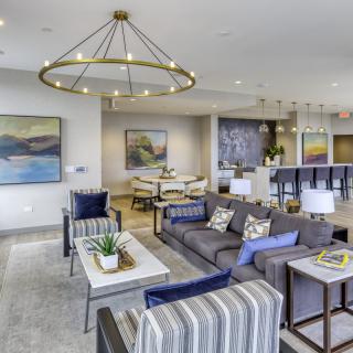 A modern living room with stylish furniture, artwork on the walls, and a large chandelier providing lighting.