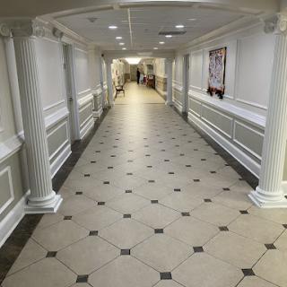A spacious and well-lit hallway with decorative columns and tiled flooring.