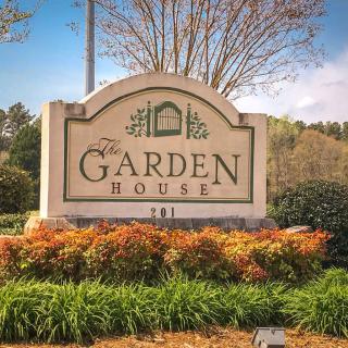 Entrance sign for The Garden House surrounded by landscaped greenery.