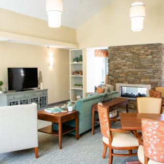 A modern living room featuring a cozy sitting area, dining table, and stone fireplace.