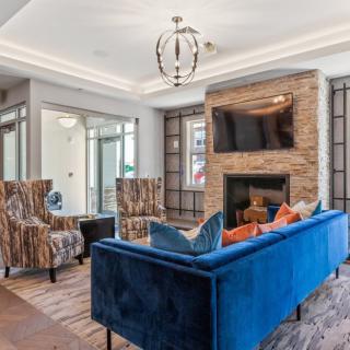 A modern living room with a blue sofa, stone fireplace, and stylish decor.